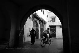 Image du Maroc Professionnelle de  Dans une rue des Habous, la succession des balèvres, moulure, arches, portiques et autres éléments décoratifs, projetent les visiteurs dans l’ardeur avec un élan de force et de fierté d’une époque révolue. Conçu par les architectes Auguste Cadet et Edmond Brion d’après l’ébauche d’un premier plan-masse dû à Albert Laprade, le quartier fait partie des endroits les plus pittoresques de Casablanca, il fut La construction n’avait commencé qu’après la première guerre mondiale. Situé près du Palais Royale, ce joyau architectural fait partie du patrimoine architectural de la ville, Samedi 8 Novembre 2008. Au centre le minaret de La mosquée Ben Youssef. (Photo / Abdeljalil Bounhar)
 